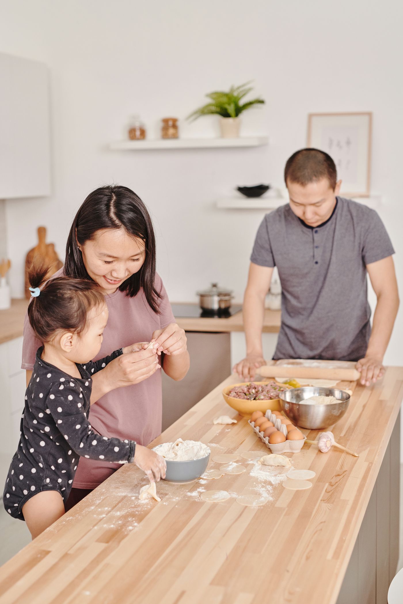 一家人在厨房一起准备饭菜,孩子和父母共同包饺子